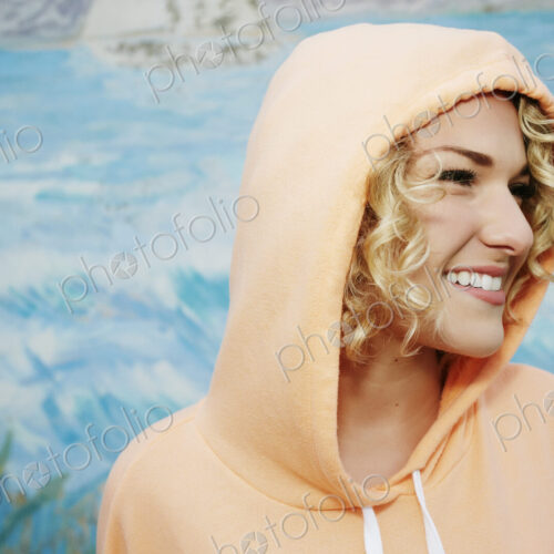 Profile portrait of smiling woman with curly blond hair wearing pink hoodie. Profile portrait of smiling woman with curly blond hair wearing pink hoodie.