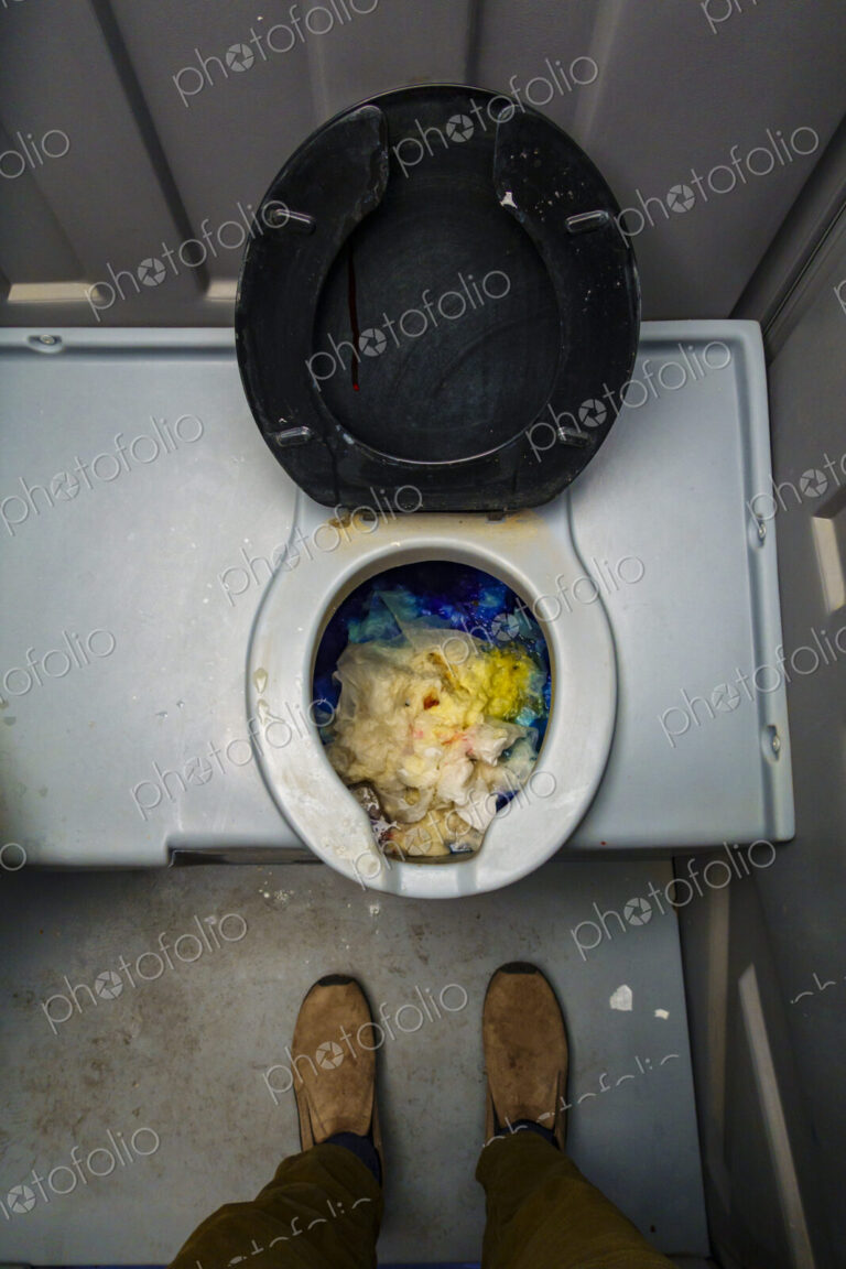 Public reststop toilet, view from above of a dirty blocked bowl full of toilet paper.