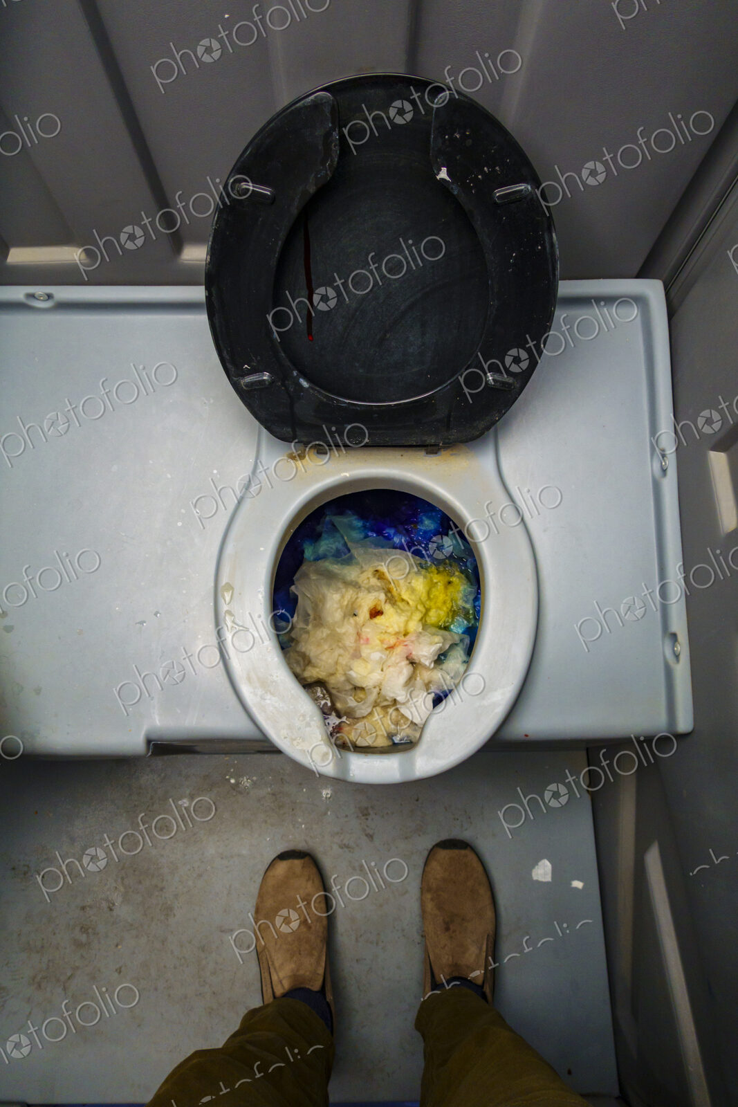 Public reststop toilet, view from above of a dirty blocked bowl full of toilet paper.