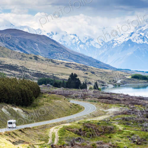 RV driving near mountains and lake in remote landscape RV driving near mountains and lake in remote landscape