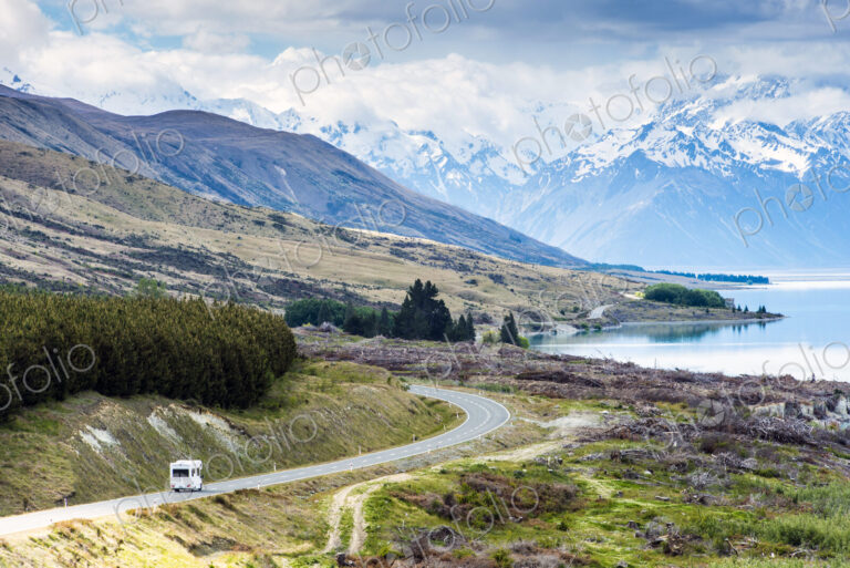 RV driving near mountains and lake in remote landscape