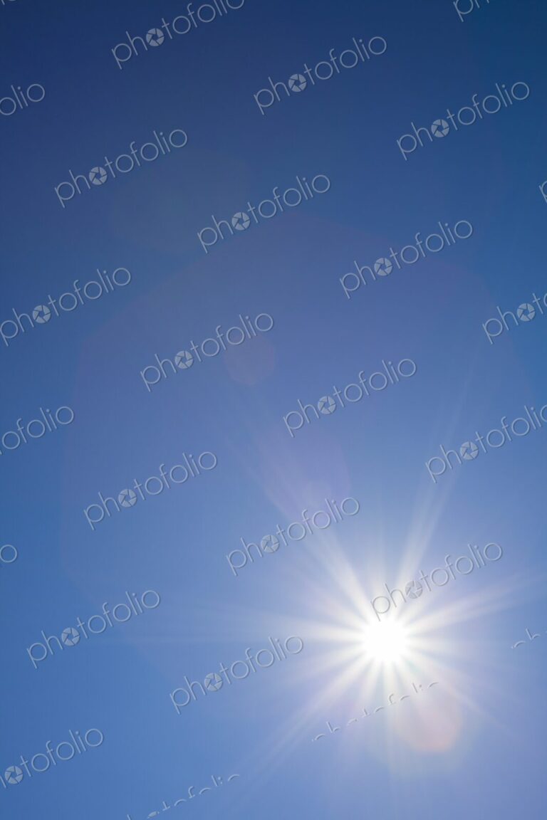 Radiant sunburst with lens flare effects captured against a cloudless blue sky on a…