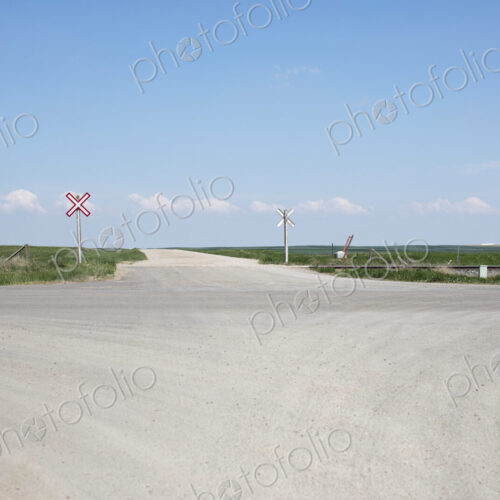 Railroad crossing along rural road and farmland,