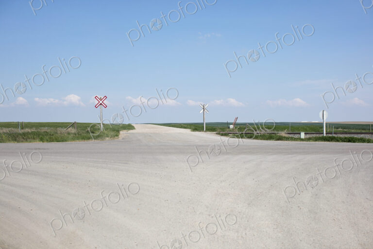 Railroad crossing along rural road and farmland,