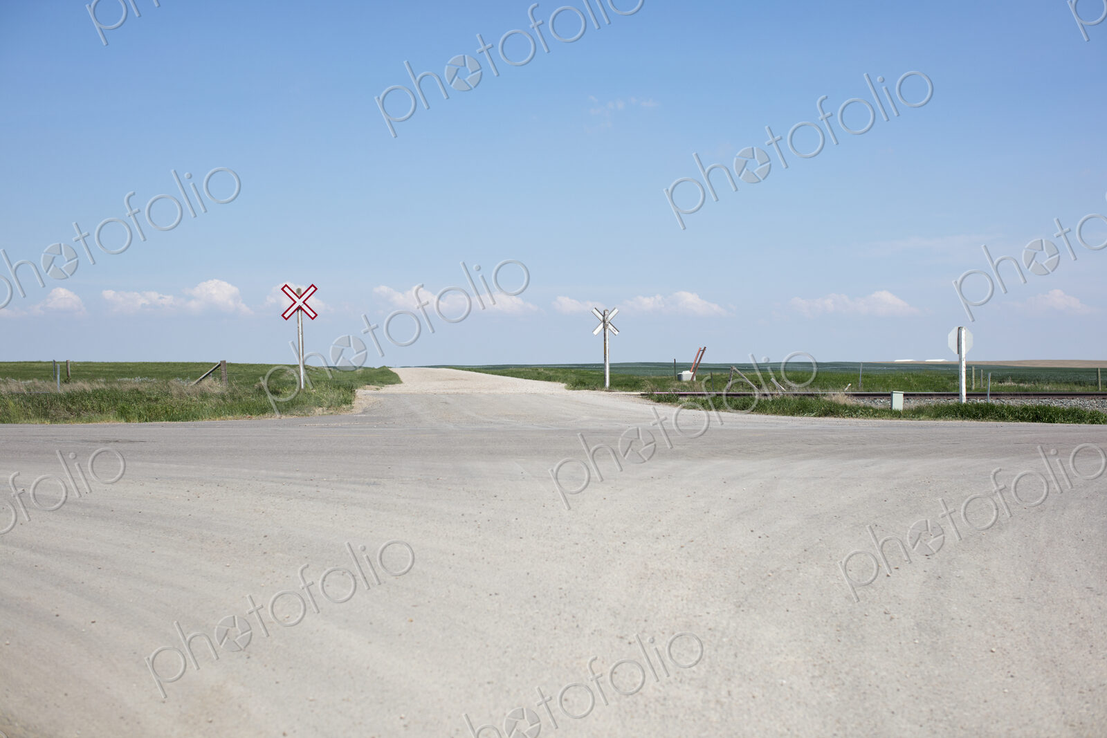 Railroad crossing along rural road and farmland,