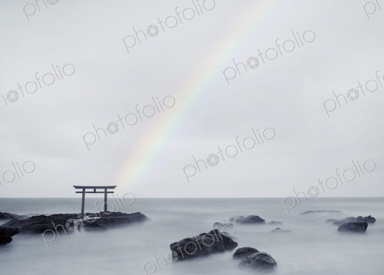 Rainbow over tall Torii gate on rocks in the middle of a lake.