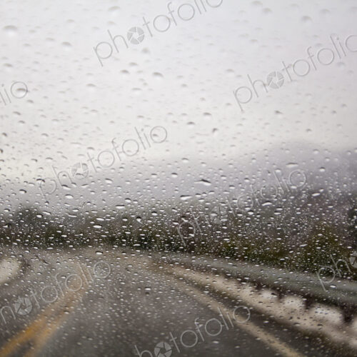 Raindrops on windshield on two lane highway.