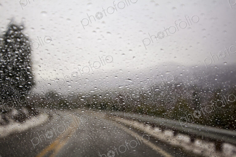 Raindrops on windshield on two lane highway.