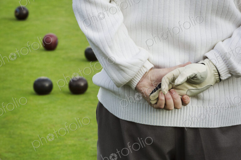 Rear view, a man standing with his hands clasped behind him, one hand in a playing…