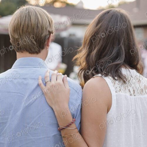 Rear view of a couple standing side by side in a garden, woman touching man's shoulder.