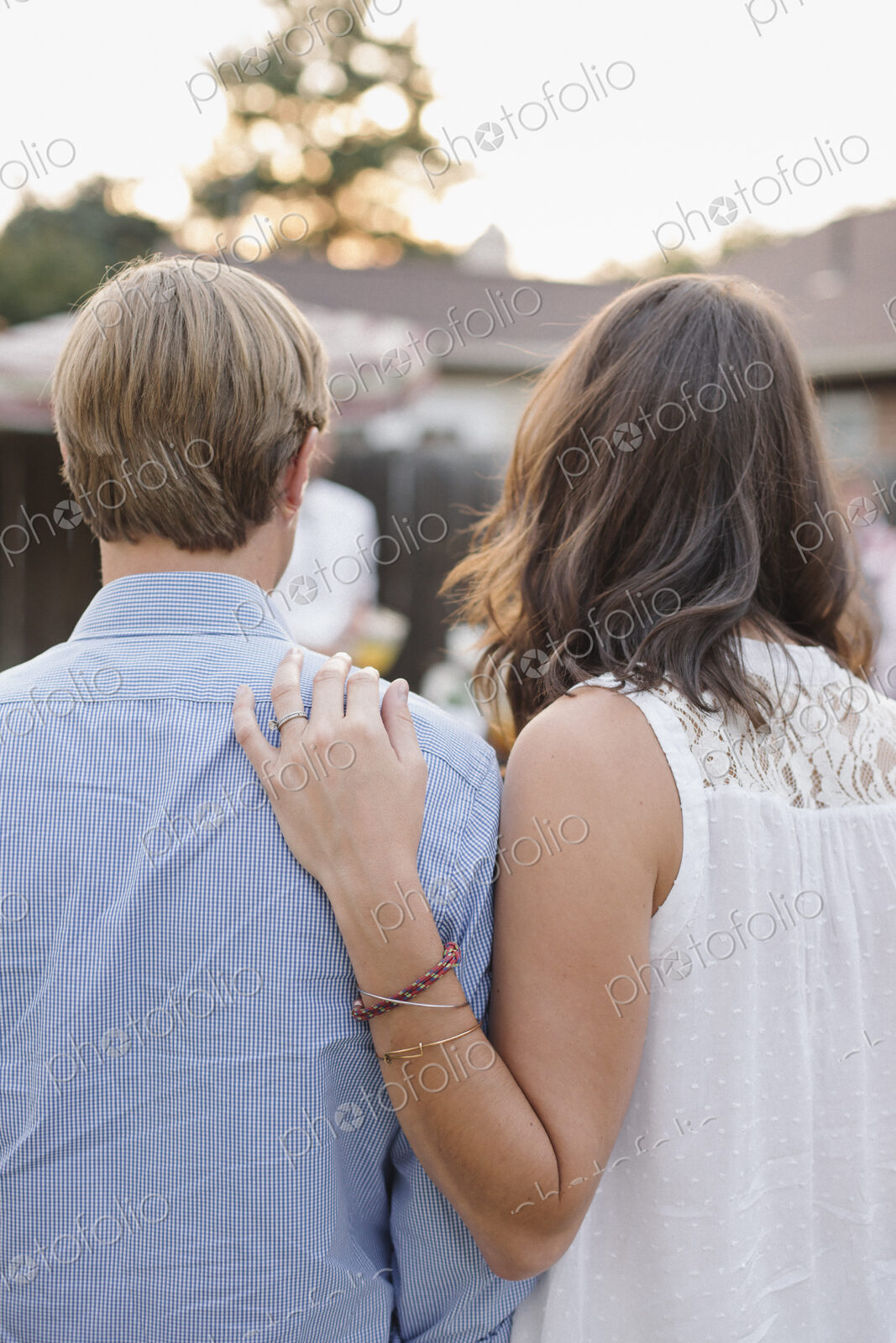 Rear view of a couple standing side by side in a garden, woman touching man’s shoulder.