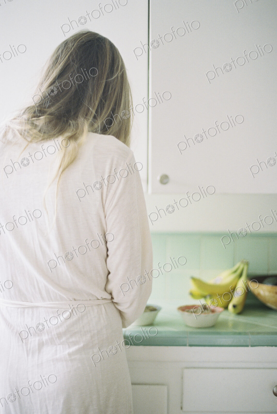 Rear view of a woman standing in a kitchen, preparing breakfast.
