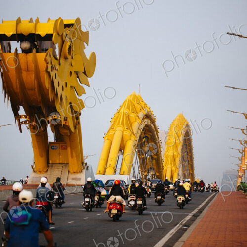 Rear view of commuters on motorcycles crossing bridge in the shape of a dragon. Rear view of commuters on motorcycles crossing bridge in the shape of a dragon.