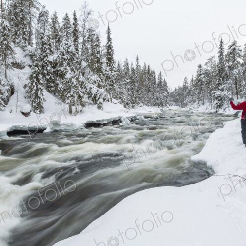Rear view of man standing by rapid in forest with snow-covered trees. Rear view of man standing by rapid in forest with snow-covered trees.