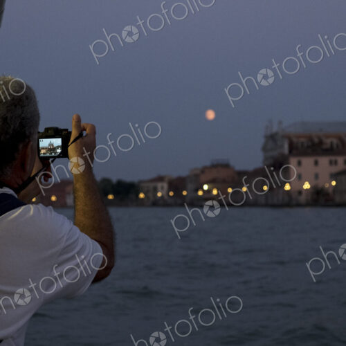 Rear view of man taking picture of the Canale Grande in Venice, Veneto, Italy, at night.