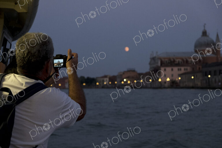Rear view of man taking picture of the Canale Grande in Venice, Veneto, Italy, at night.