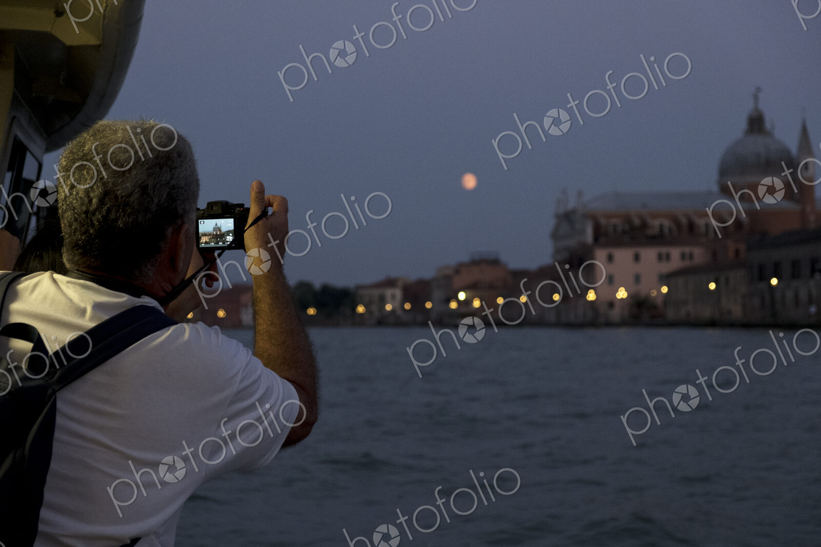Rear view of man taking picture of the Canale Grande in Venice, Veneto, Italy, at night.
