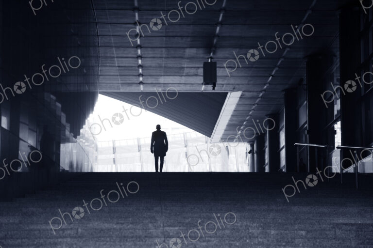 Rear view of man wearing coat and bowler hat standing at top of stairway of concrete…