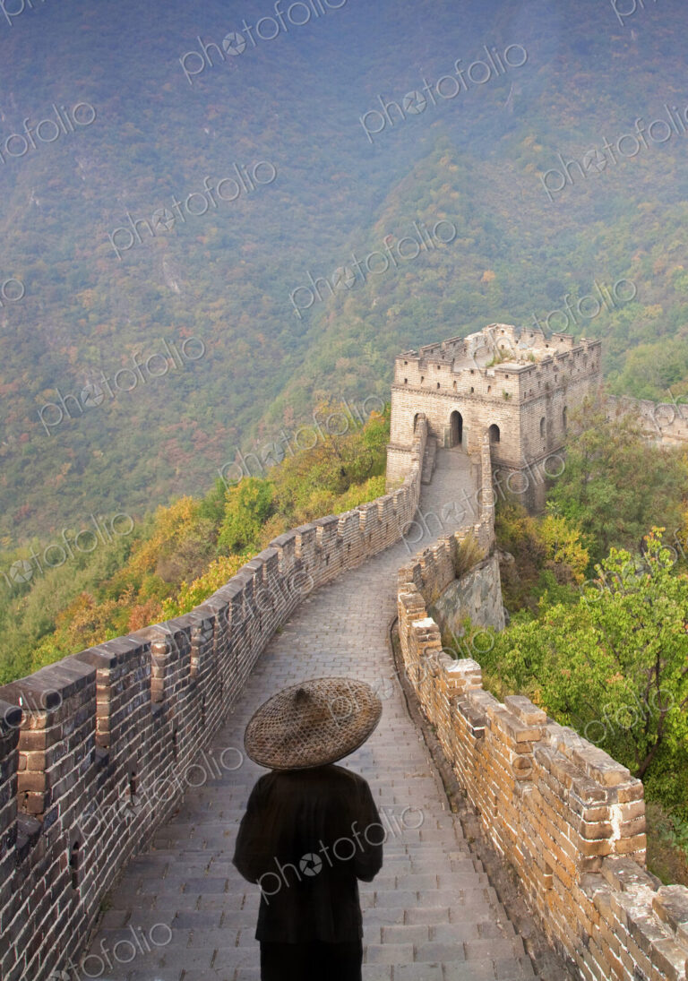 Rear view of man wearing traditional straw hat standing on Great Wall of China.