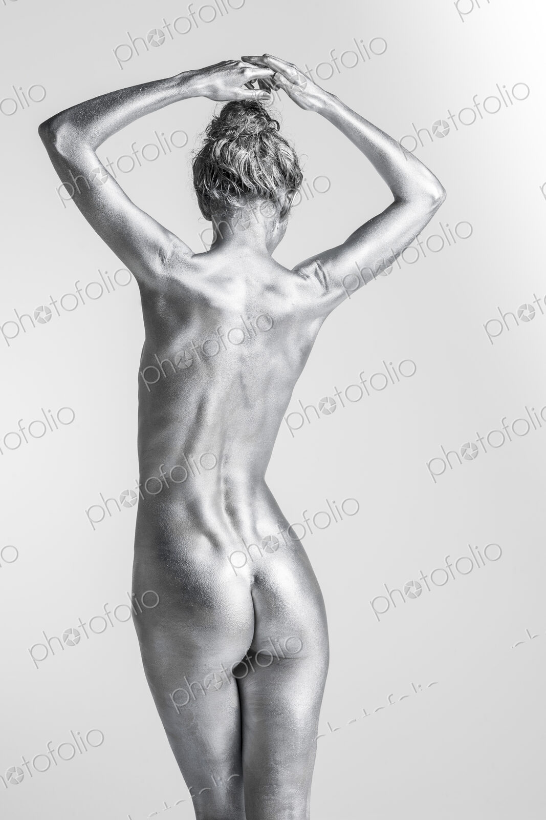 Rear view of nude Caucasian woman with silver body paint