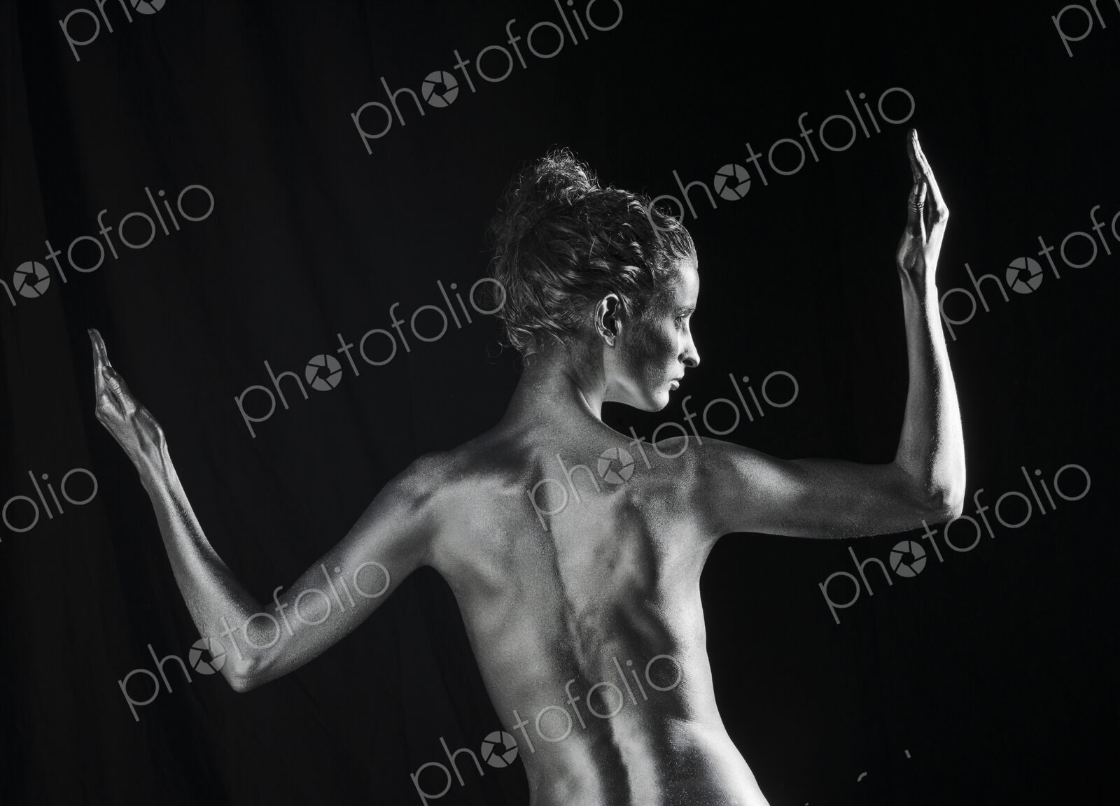 Rear view of nude Caucasian woman with silver body paint