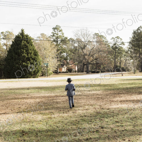 Rear view of yoing boy dressed in suit walking on lawn Rear view of yoing boy dressed in suit walking on lawn