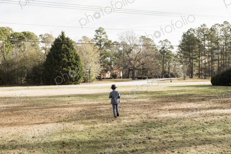 Rear view of yoing boy dressed in suit walking on lawn