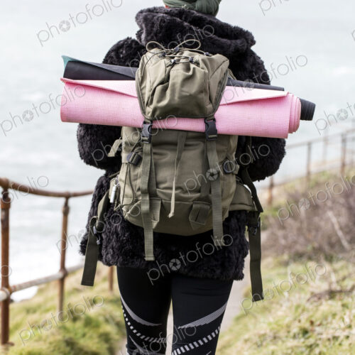 Rear view of young woman with brown hair and dreadlocks carrying backpack, walking… Rear view of young woman with brown hair and dreadlocks carrying backpack, walking…