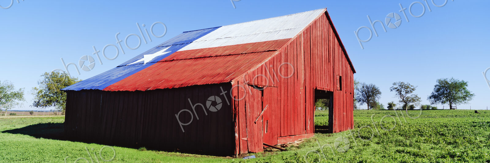 Red Barn in Field With Texas Flag on Roof