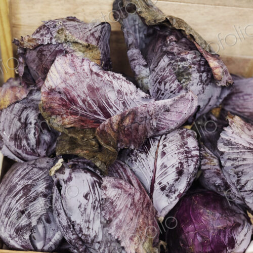 Red cabbages piled up in a wooden crate.