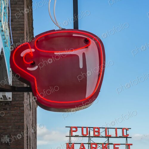 Red neon coffee cup sign glows beside the iconic Public Market sign at Pike Place… Red neon coffee cup sign glows beside the iconic Public Market sign at Pike Place…