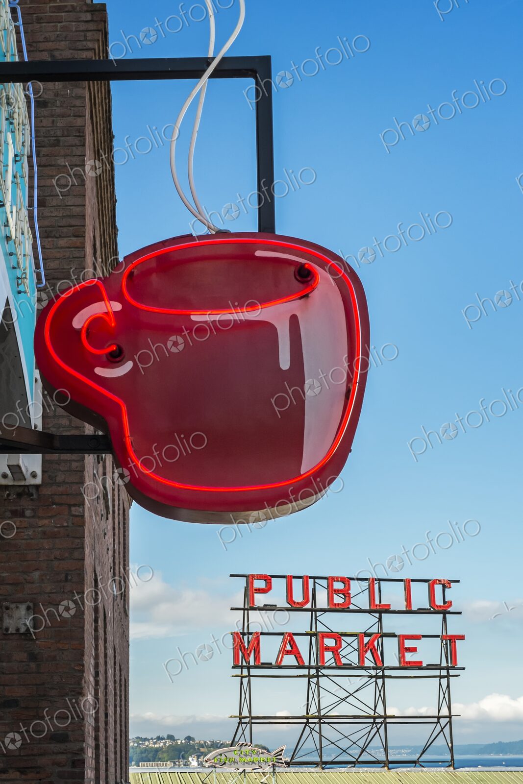 Red neon coffee cup sign glows beside the iconic Public Market sign at Pike Place…