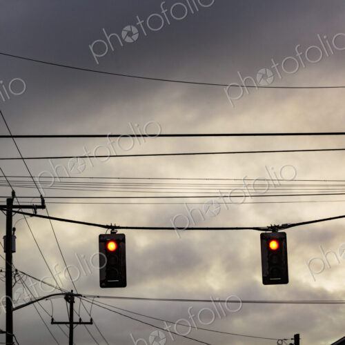 Red stoplight from a low angle view, and overhead cables.