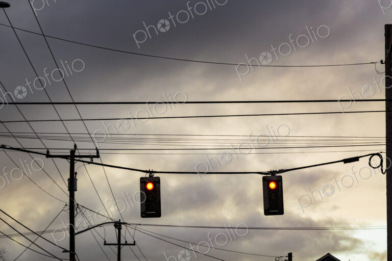 Red stoplight from a low angle view, and overhead cables.