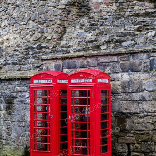 Red telephone boxes in front of ancient stone wall. Red telephone boxes in front of ancient stone wall.