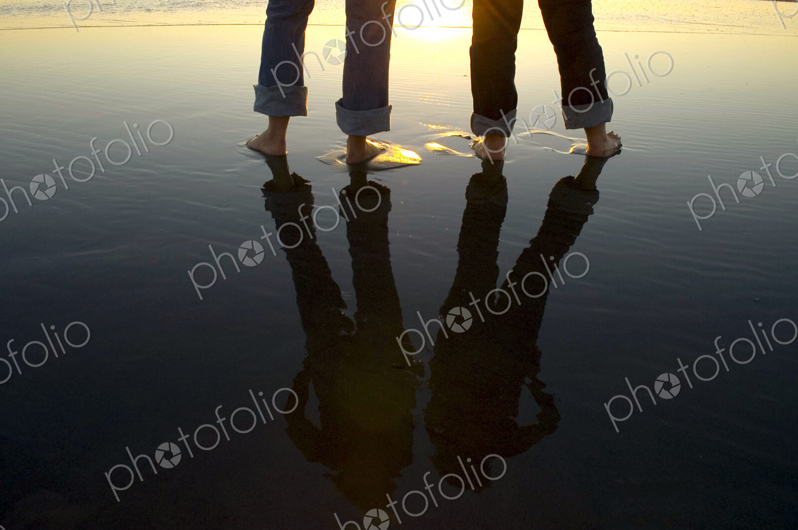 Reflection of legs in water at beach
