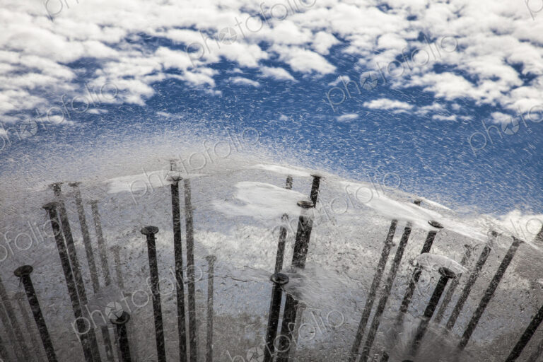 Reflection of sky and clouds in water surface of a modern fountain.