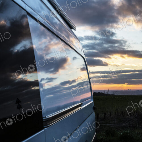 Reflections of clouds on camper van window at sunset. Reflections of clouds on camper van window at sunset.