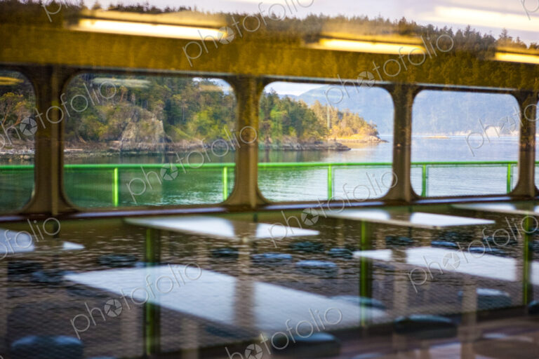 Reflections on the roof and interior of a ferry from the shore and the water.