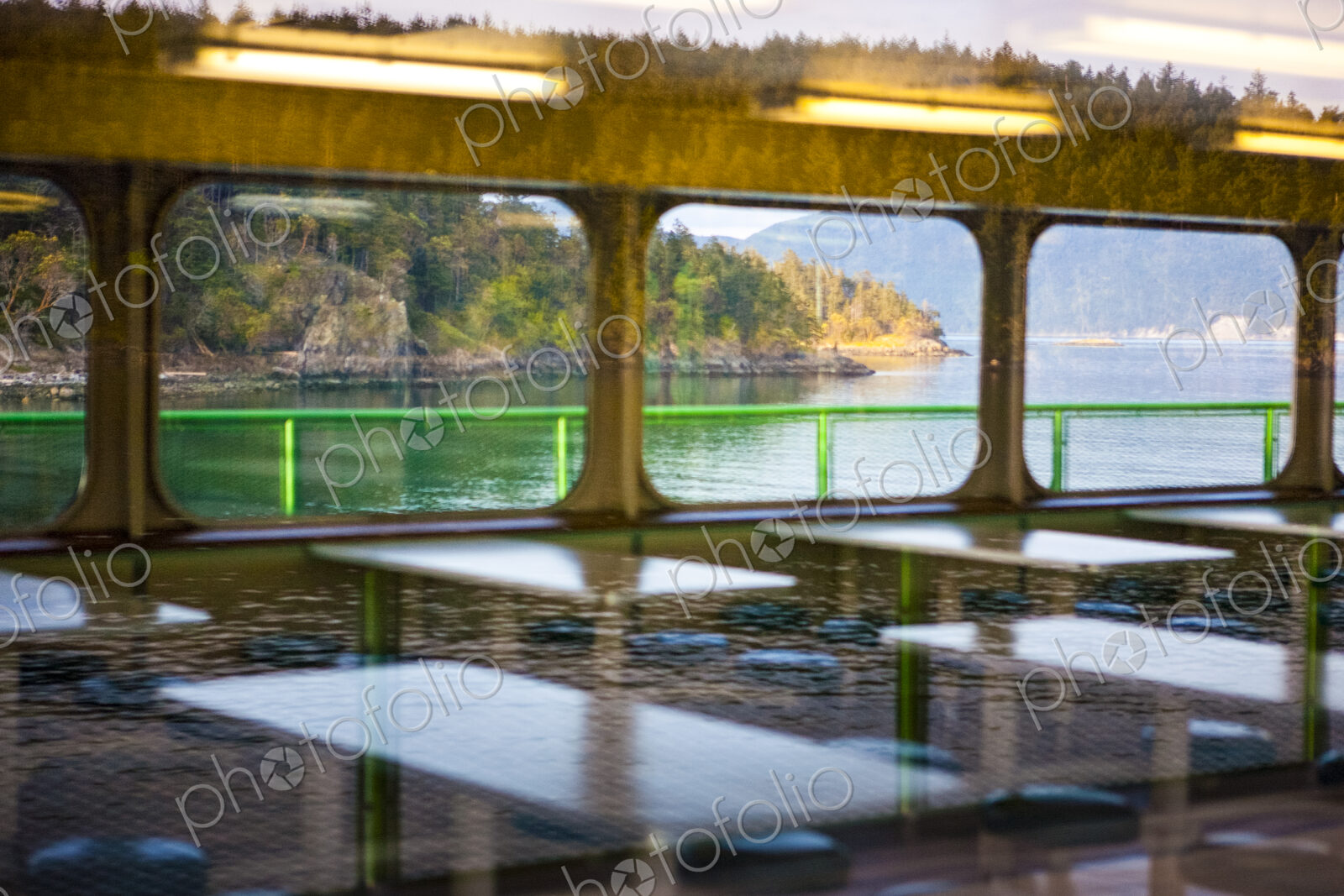 Reflections on the roof and interior of a ferry from the shore and the water.