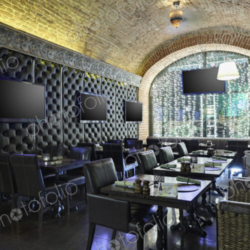 Restaurant interior with TV screens on leather covered wall. Restaurant interior with TV screens on leather covered wall.