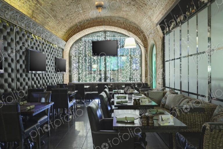 Restaurant interior with one wall made of glass and other of leather.