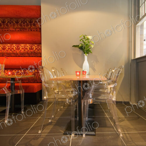 Restaurant interior,with perspex chairs,wooden tables,and a tiled floor, and service…