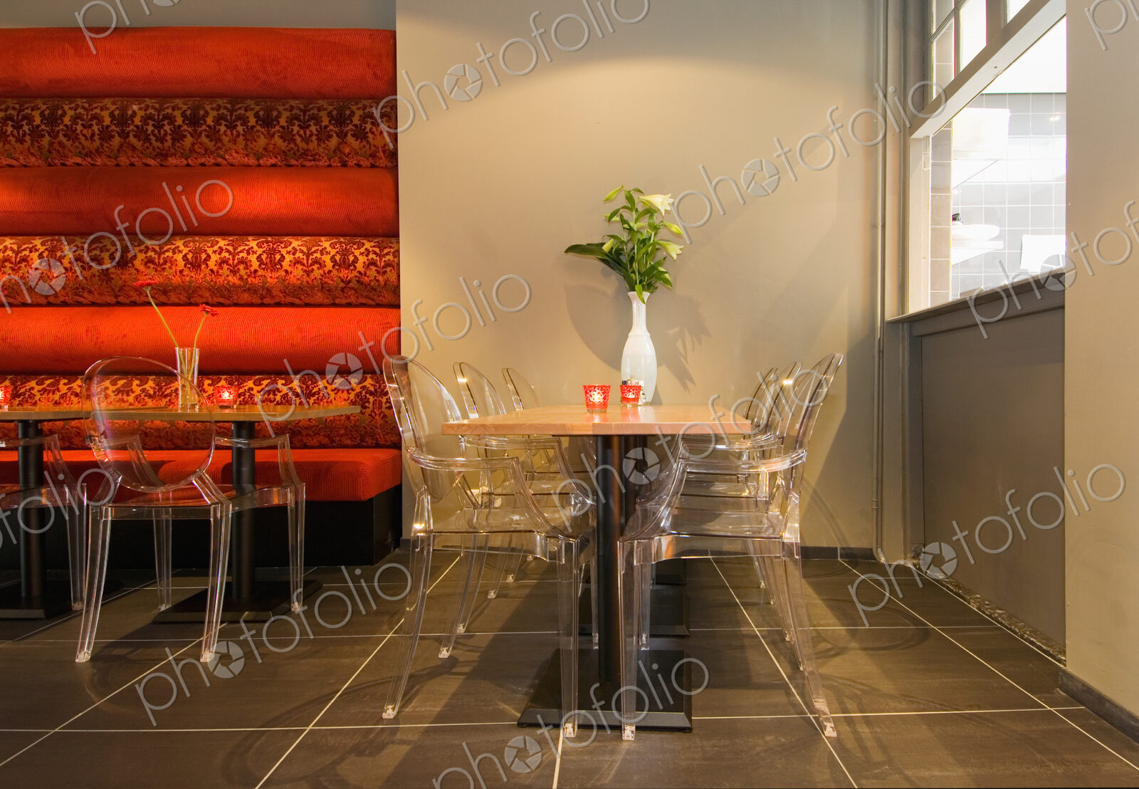Restaurant interior,with perspex chairs,wooden tables,and a tiled floor, and service…