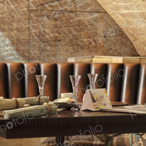 Restaurant leather lounge with three glasses on table.