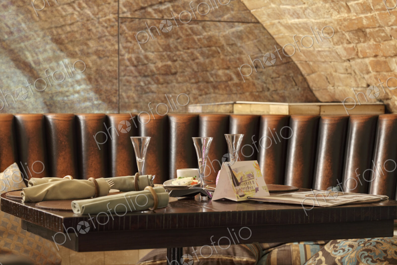 Restaurant leather lounge with three glasses on table.