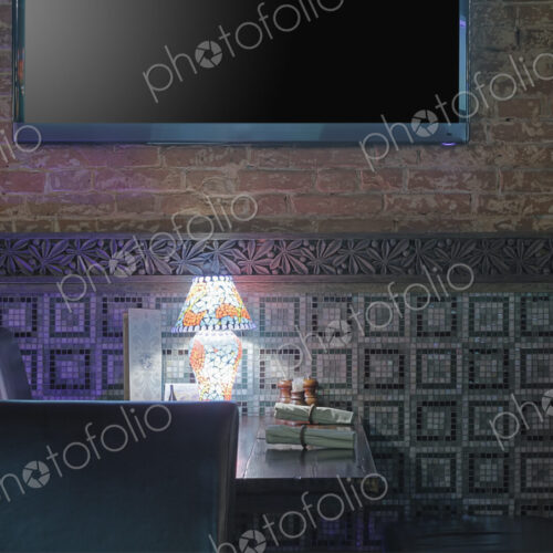 Restaurant table with lamp under flat screen TV.