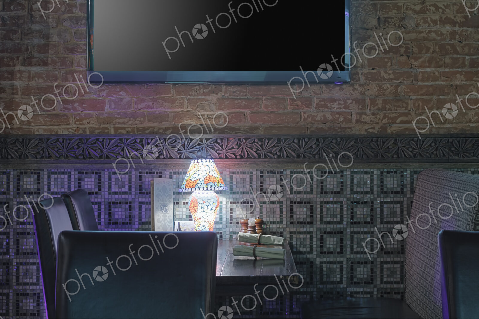 Restaurant table with lamp under flat screen TV.