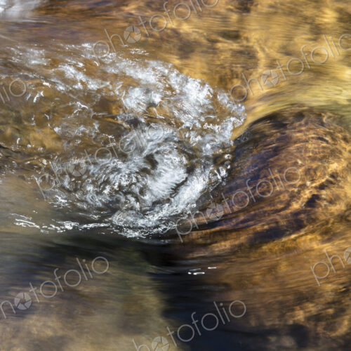 River water abstract, long exposure of river water flowing over boulders and rocks