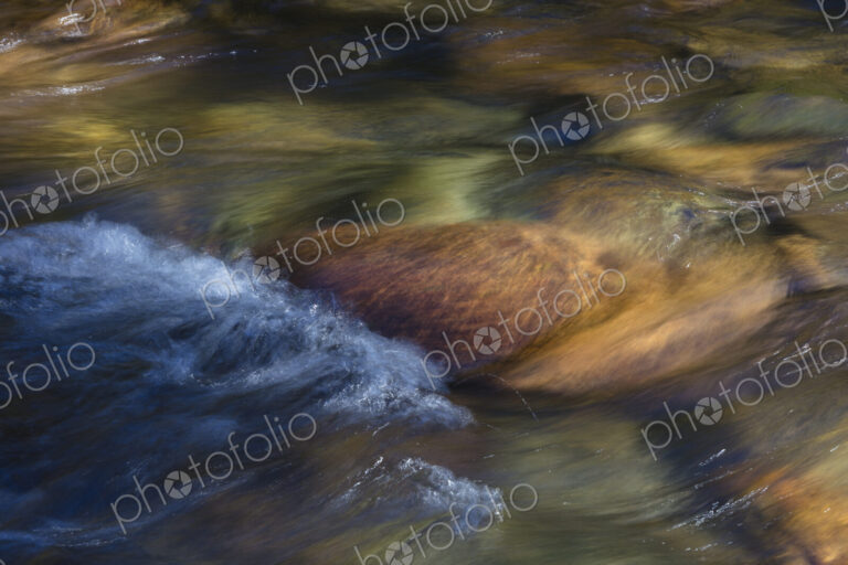 River water abstract, long exposure of river water flowing over boulders and rocks